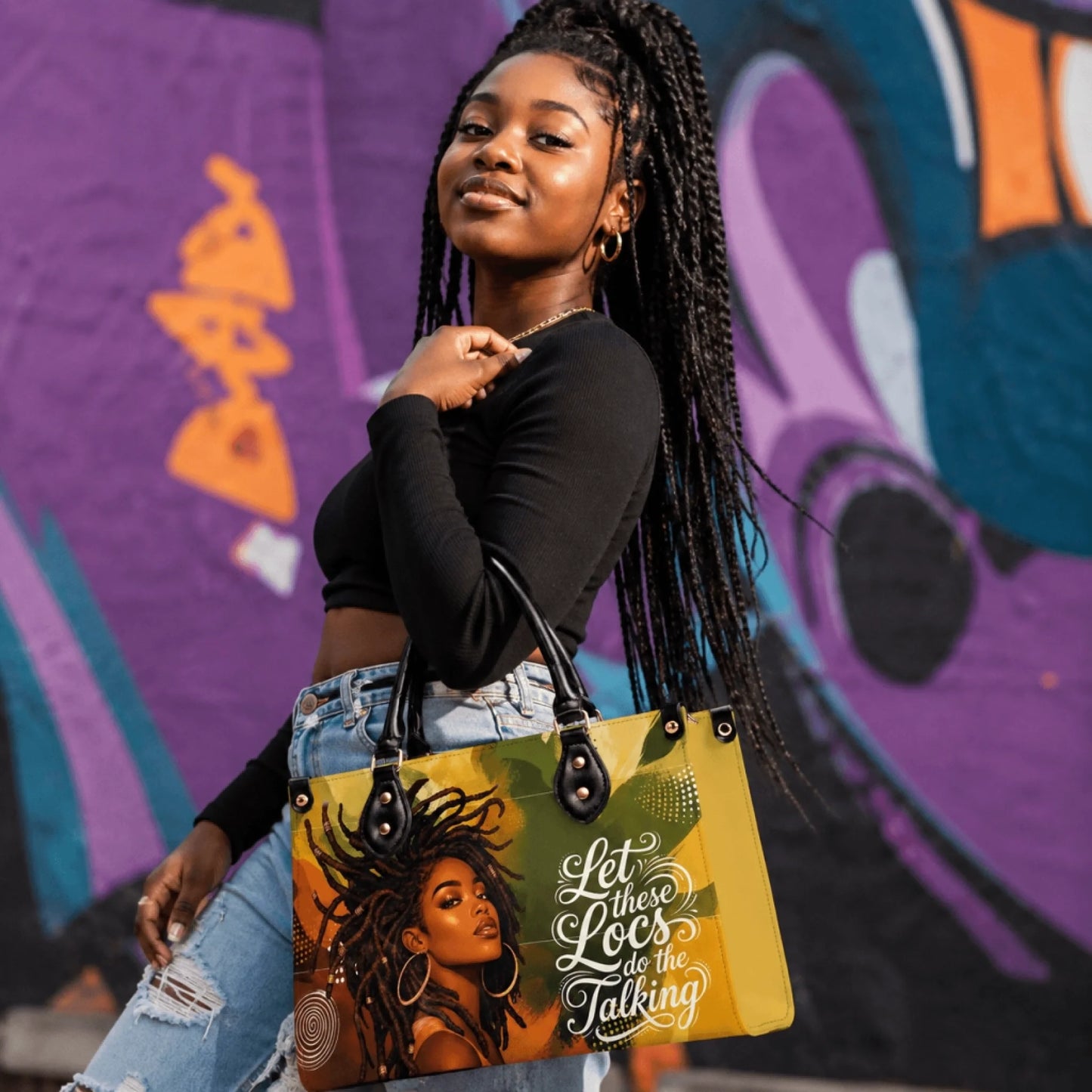 Woman wearing stylish jeans and holding a unique handbag with locs artwork and the motivational quote Let these Locs do the Talking.
