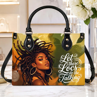 A beautifully designed handbag displayed on a table featuring bold artwork of a woman with locs and encouraging lettering.