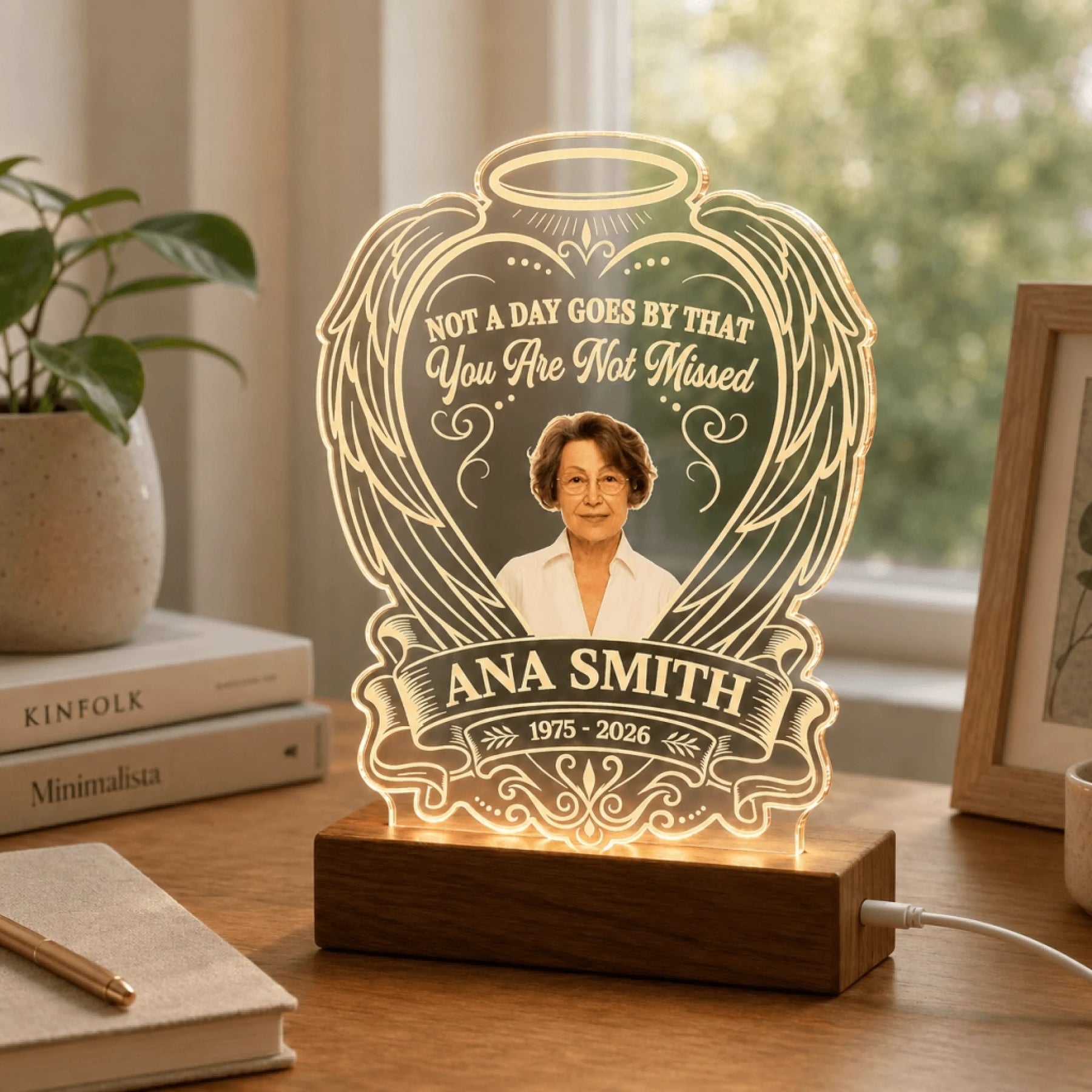 Personalized memorial acrylic LED lamp displayed on a wooden desk, accented with nearby books and plant.