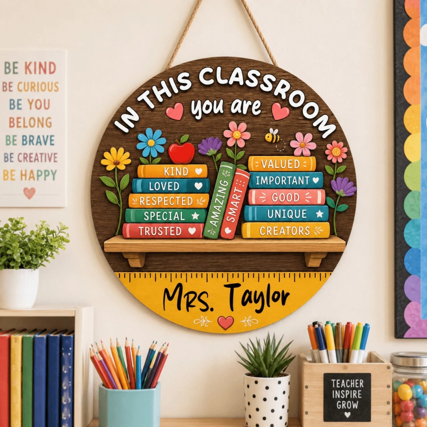 A round wooden 'In This Classroom You Are' door sign personalized for Mrs. Taylor, featuring colorful book-themed motivational words.