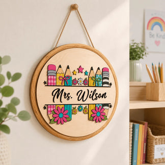 Custom round wooden sign for teachers hanging in a classroom, featuring colorful pencil and floral pencil designs.