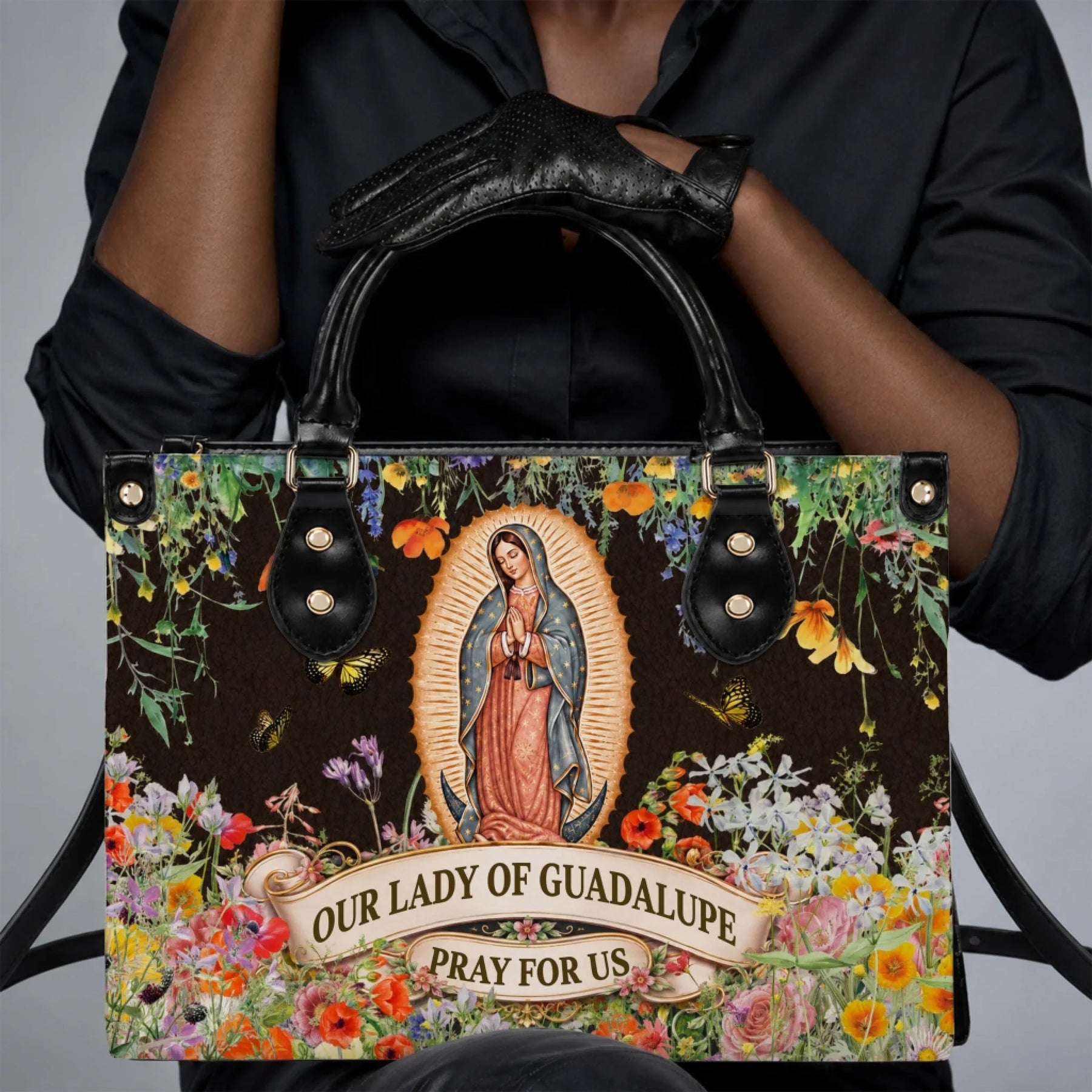 A person holding an Our Lady of Guadalupe floral printed handbag, suitable for religious celebrations or daily wear.