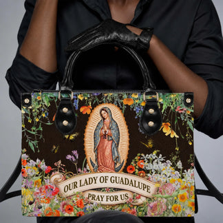 A person holding an Our Lady of Guadalupe floral printed handbag, suitable for religious celebrations or daily wear.