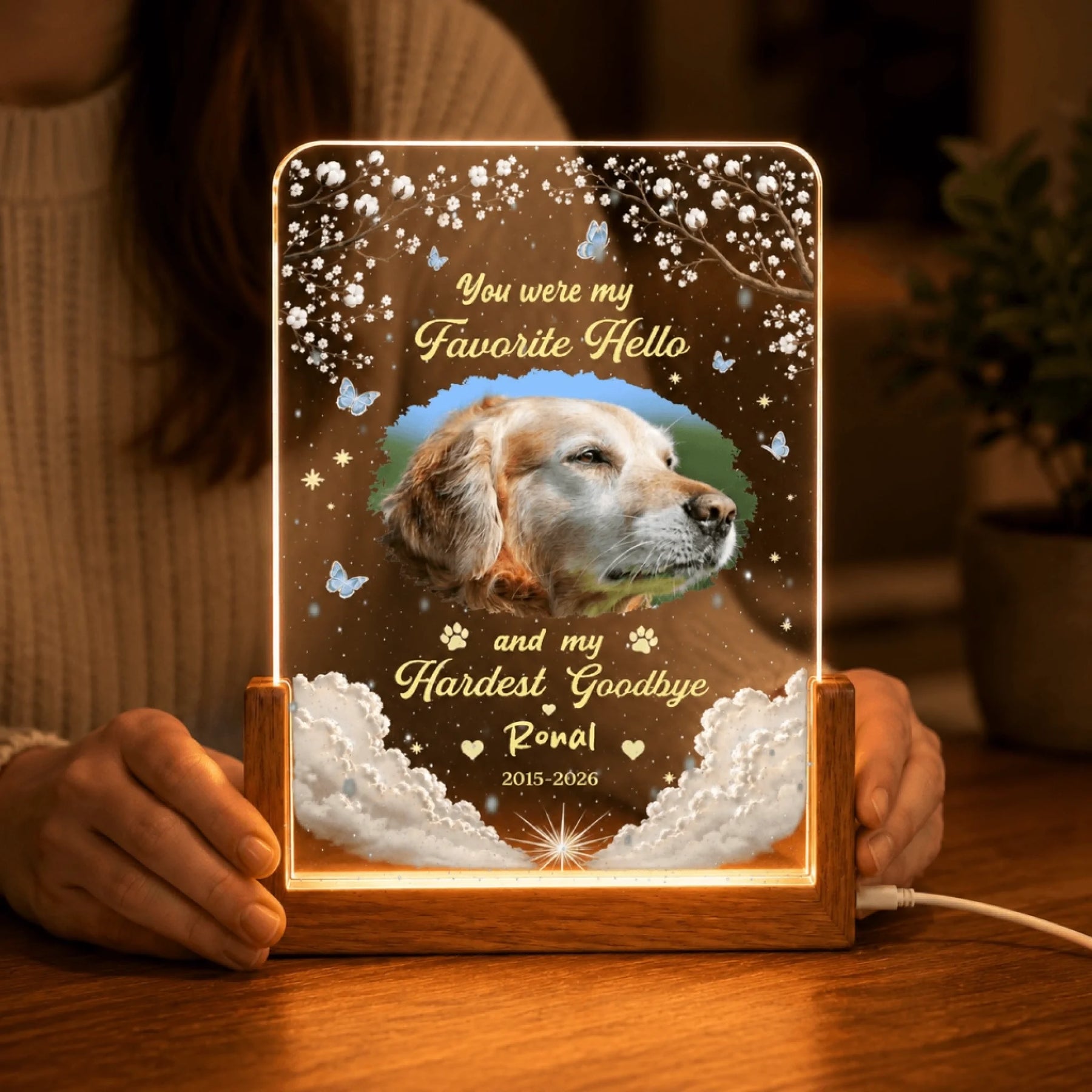Close up of a person holding a custom pet memorial night light with a golden retriever photo and date engraving.