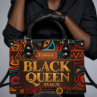 Close up of hands wearing black gloves holding a personalized Black Queen Magic shoulder bag with cultural art motifs.