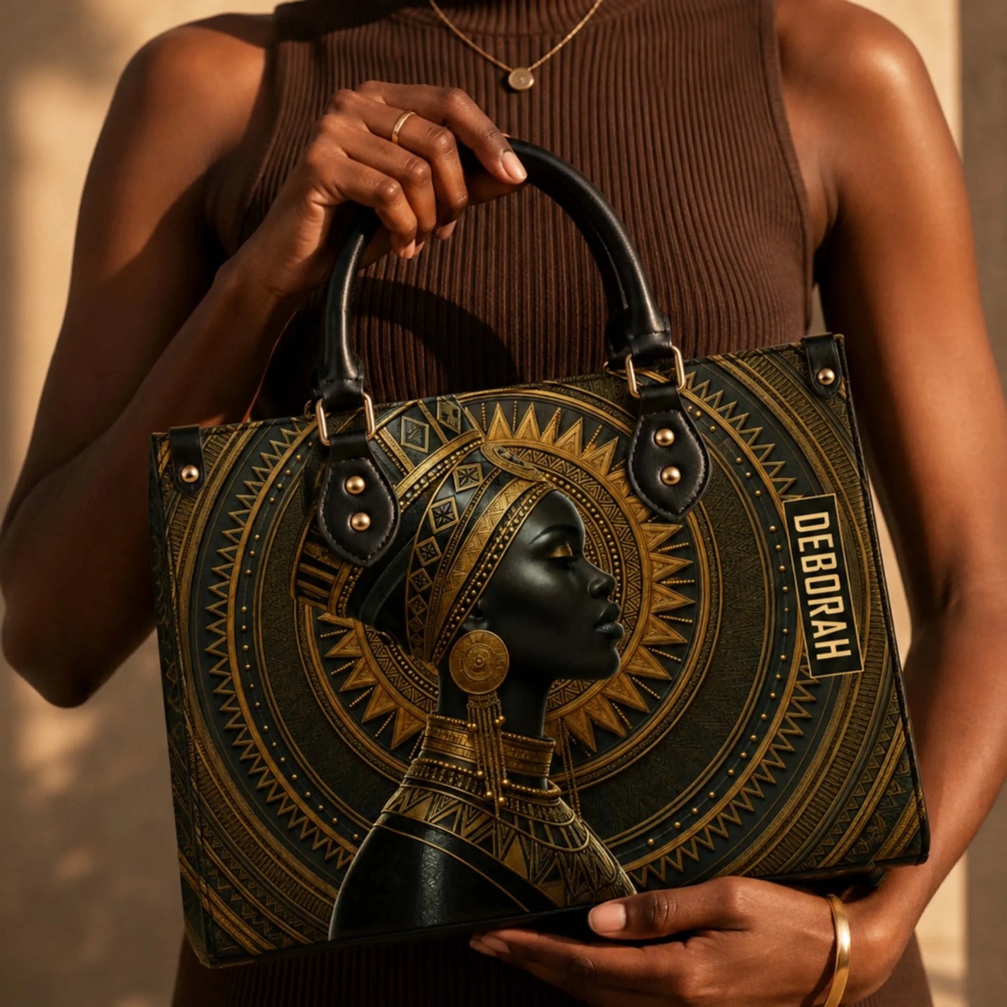 Close up of a personalized African queen handbag held by a woman wearing a brown outfit showcasing custom name art.