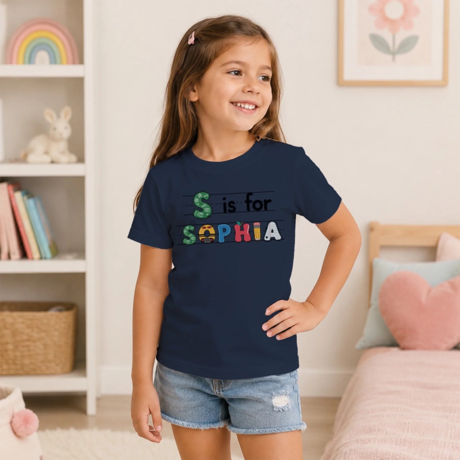 A young girl wearing a navy blue back to school t-shirt featuring her custom name Sophia in artistic colorful letters.