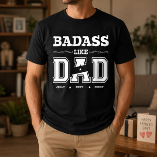 Person wearing a black t-shirt with 'BADASS LIKE DAD' text in a home setting.