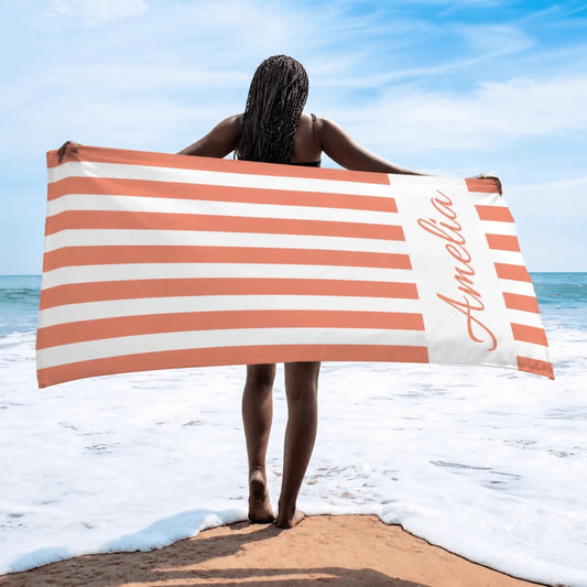 A personalized beach towel featuring coral and white stripes with the custom name Amelia, perfect for summer vacations.