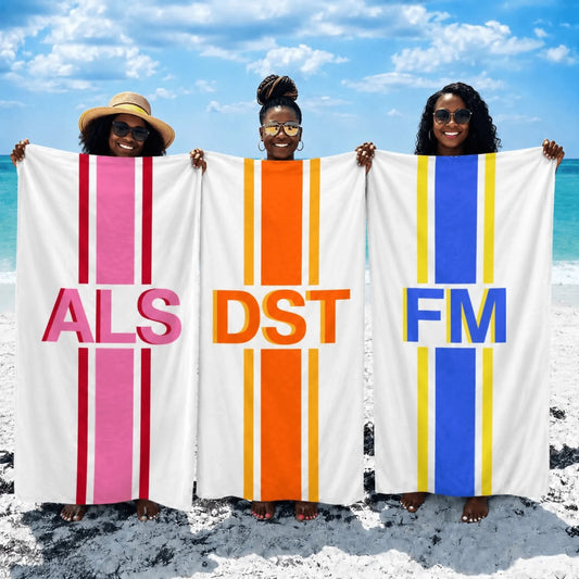 Three women holding personalized beach towels featuring custom letter monograms on striped backgrounds for summer vacations.