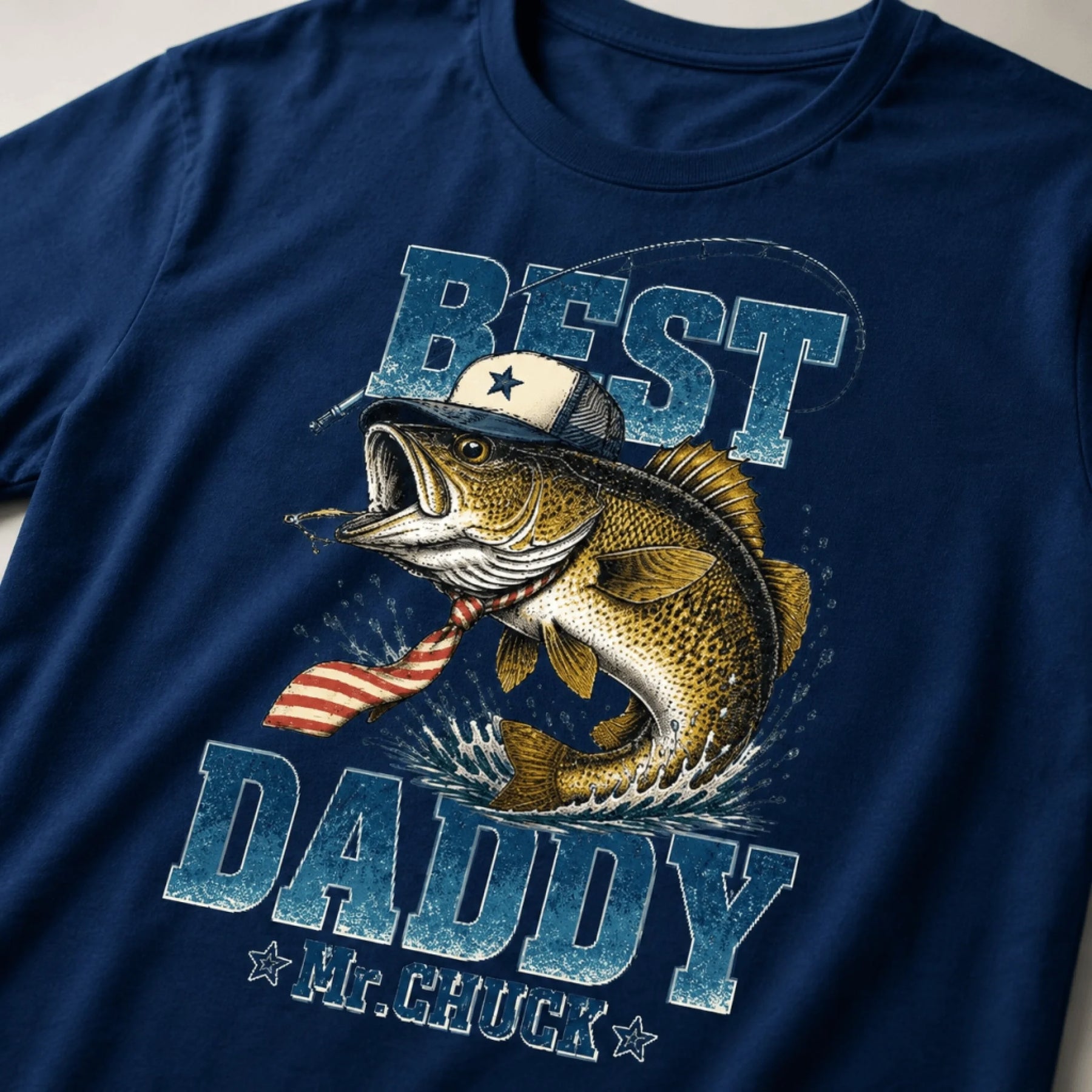 Close up of a navy t-shirt featuring a stylized fish in a hat and tie with Best Daddy Mr Chuck fishing themed design.