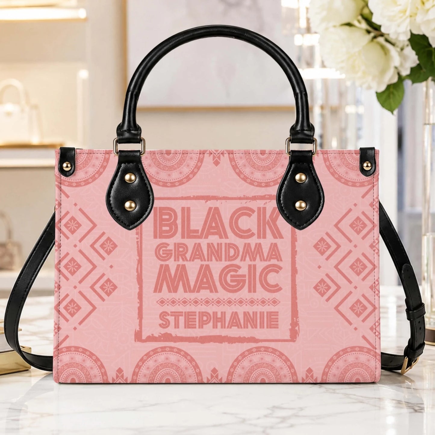 A stylish personalized pink handbag printed with Black Grandma Magic text and Stephanie name in a bright home interior.