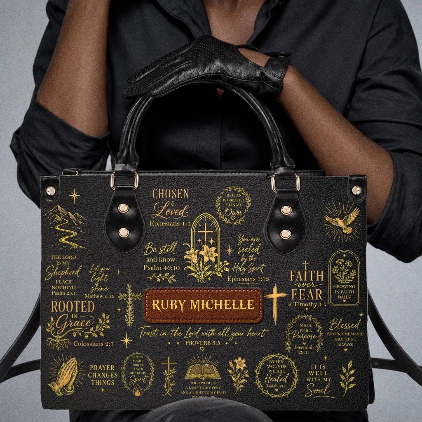 Black handbag with custom name Ruby Michelle and elegant gold religious prints, perfect for a faith inspired gift.