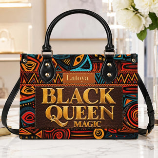 A stylish Black Queen Magic personalized handbag display with a detailed African tribal pattern and gold typography.