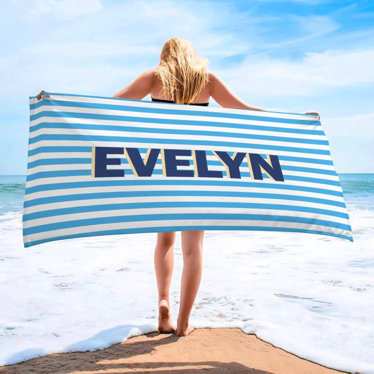 Woman holding a custom blue and white striped beach towel featuring the name Evelyn, perfect for beach days and summer vacations.