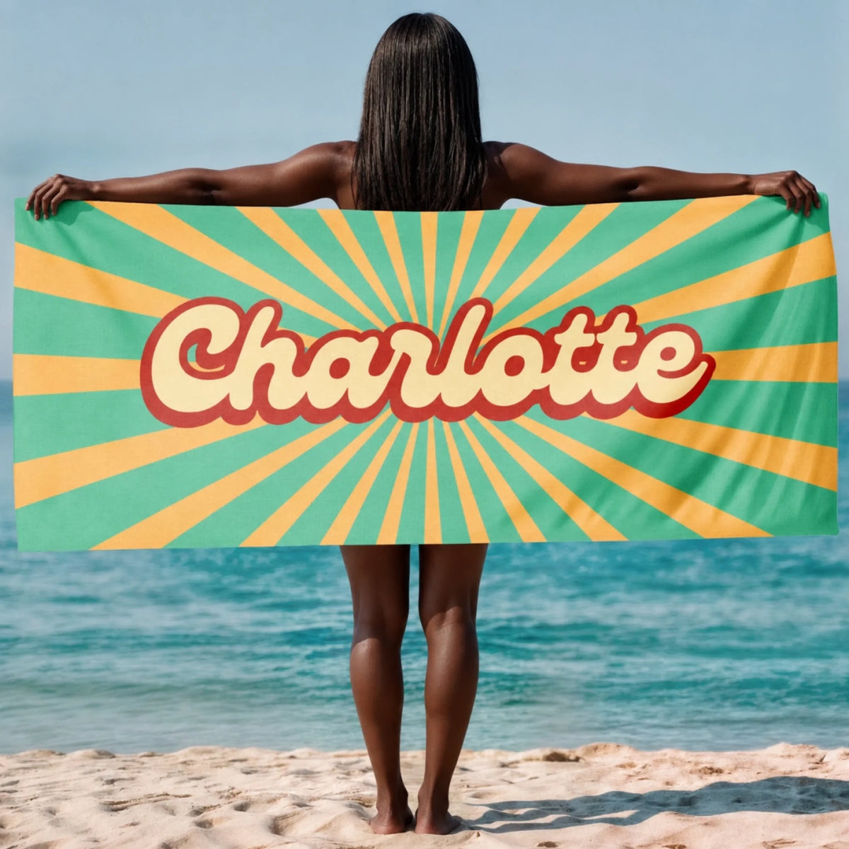 A custom beach towel featuring the name Charlotte in a retro script font over a green and yellow sunburst pattern.