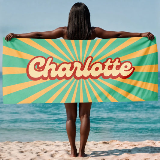 A custom beach towel featuring the name Charlotte in a retro script font over a green and yellow sunburst pattern.