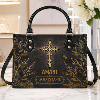 A black leather tote bag featuring a gold cross and the custom text Amari God Is Love 1 John 4 8 for religious gifts