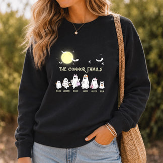 A woman wears a black personalized Halloween sweatshirt featuring a custom ghost family design with individual names.