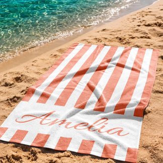 Custom name beach towel featuring stylish coral and white stripes, perfect for summer vacations or pool days.