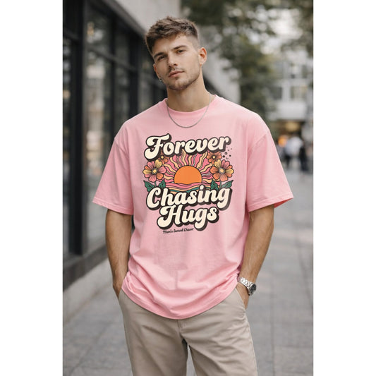 Man wearing a pink t-shirt with 'Forever Chasing Hugs' design outdoors.