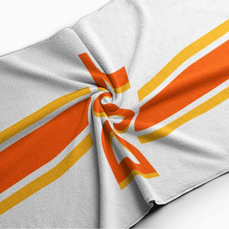 Folded personalized beach towel with a vibrant orange and yellow striped design and a custom DST monogram print