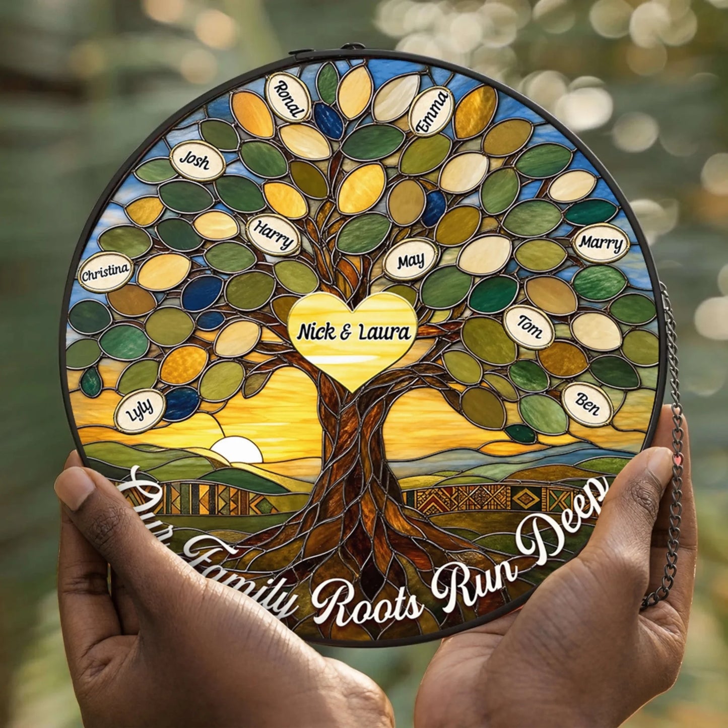 Close up of hands holding a beautiful circular stained glass suncatcher with a family tree design and the engraved quote Our Family Roots Run Deep.