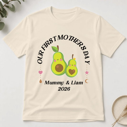 Beige t-shirt with avocado-themed design for 'Our First Mother's Day' on a light background