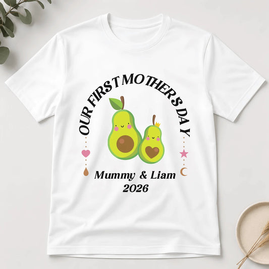 White t-shirt with avocado-themed design for 'Our First Mother's Day' on a light background
