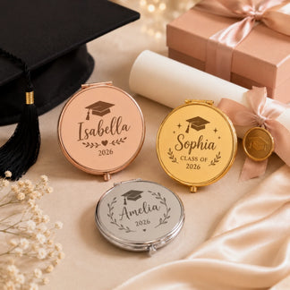Custom engraved graduation compact mirrors with names and 2026 date displayed beside a black graduation cap.