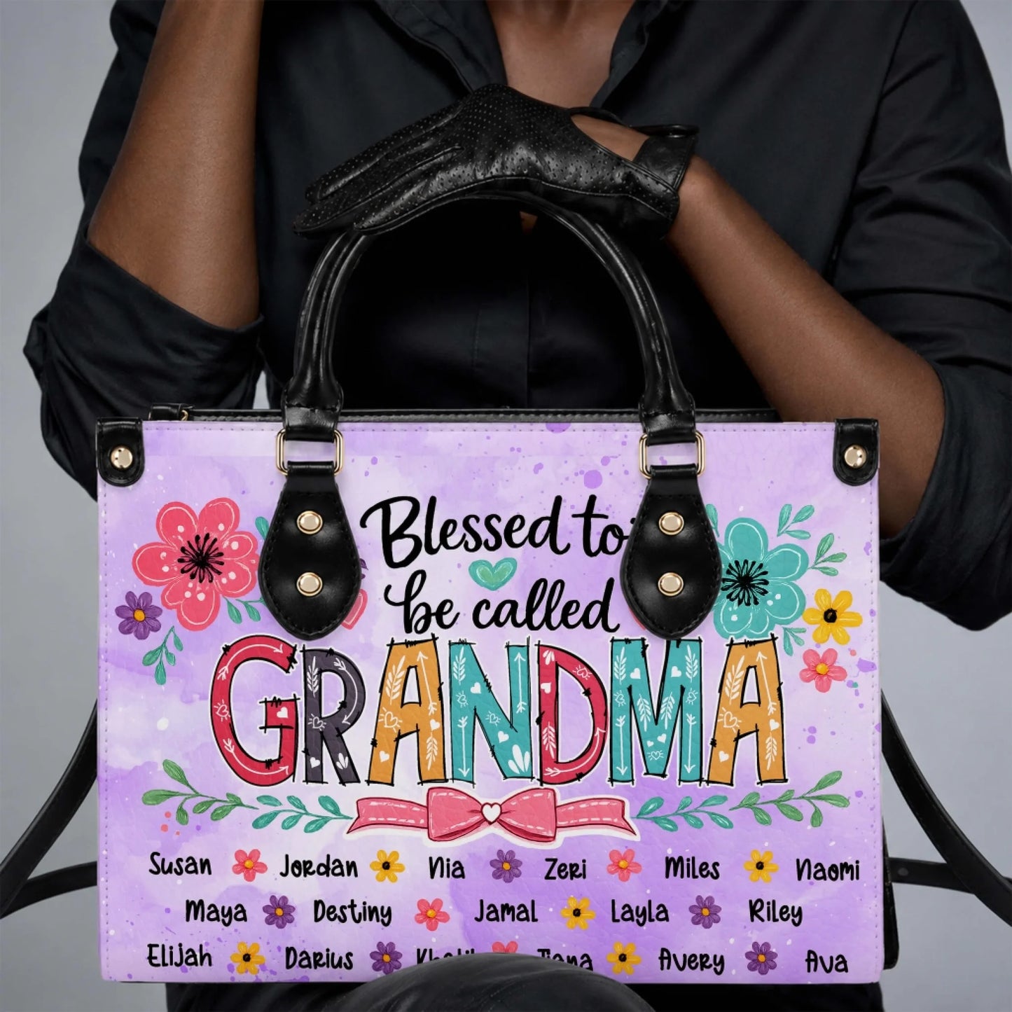Woman holding a personalized Blessed to be called Grandma floral tote bag customized with various family names.