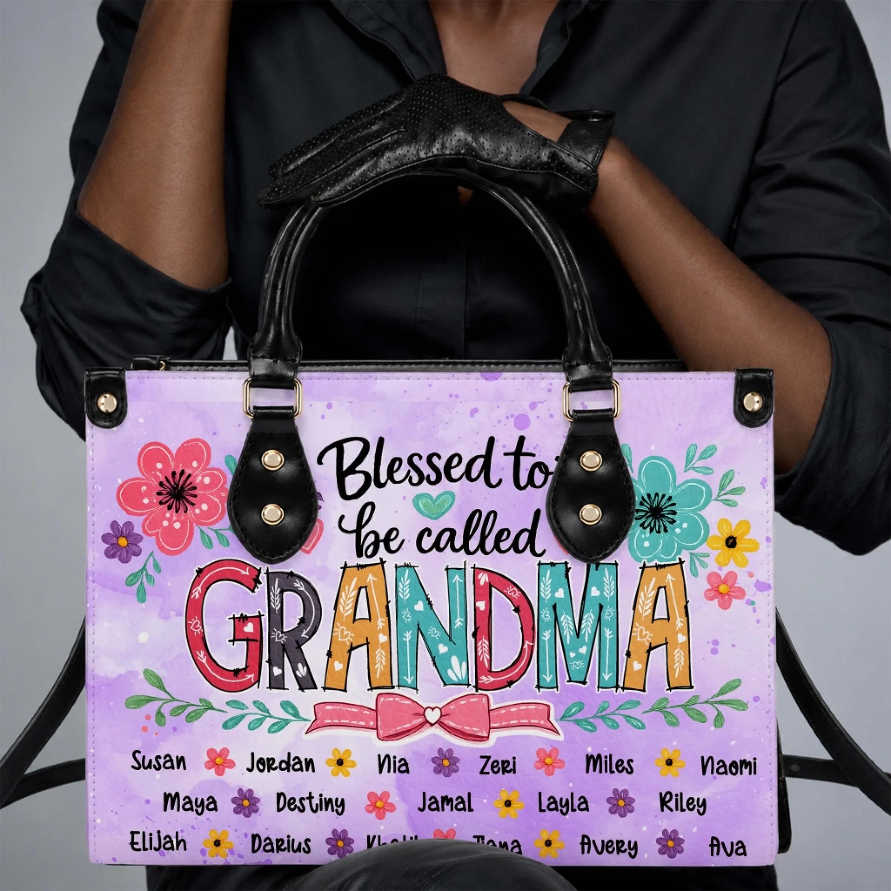 Woman holding a personalized Blessed to be called Grandma floral tote bag customized with various family names.