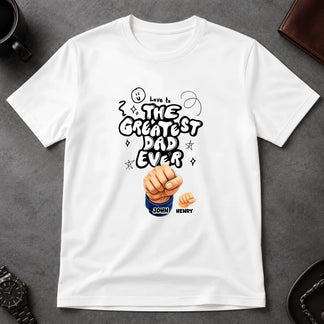 White t-shirt with 'The Greatest Dad Ever' design on a gray surface