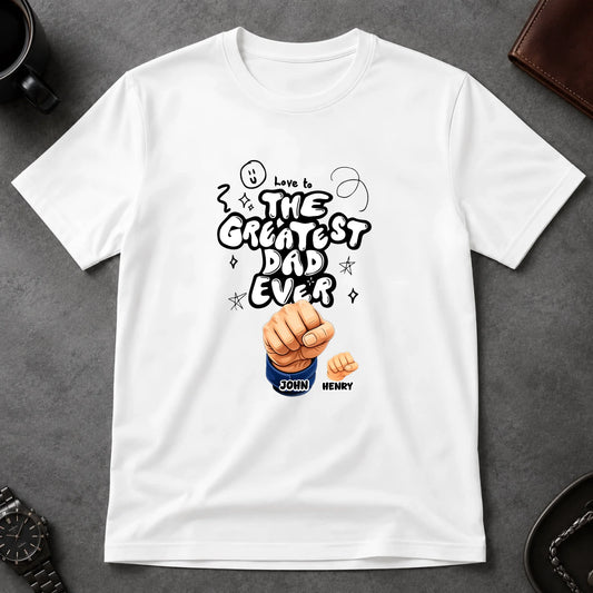 White t-shirt with 'The Greatest Dad Ever' design on a gray surface
