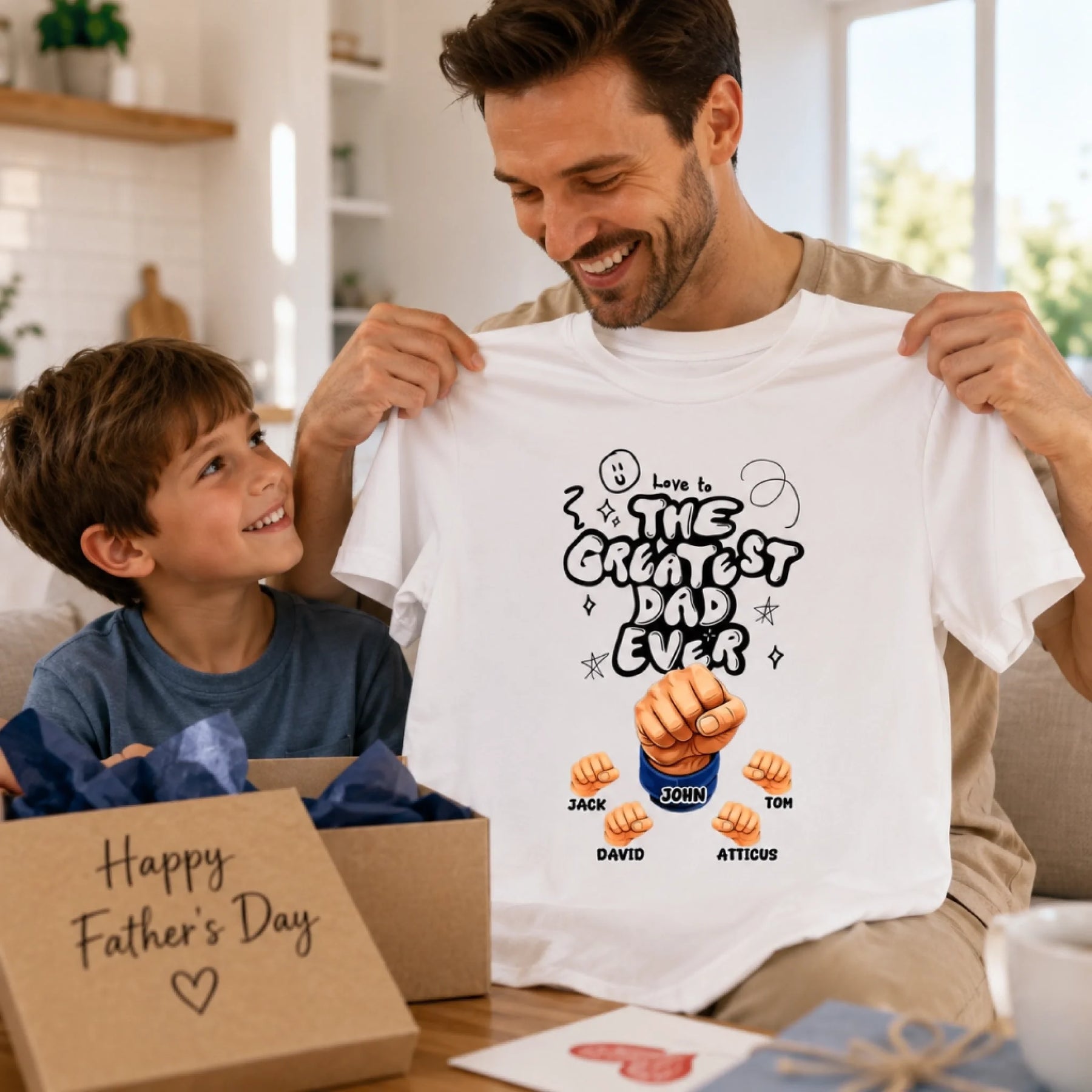 Man holding a t-shirt with 'The Greatest Dad Ever' design, smiling with a child in a home setting.