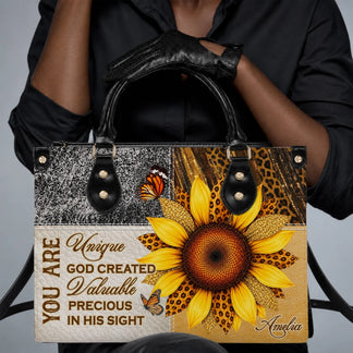 A person wearing black gloves holding a custom sunflower and butterfly tote bag with the name Amelia on the front.
