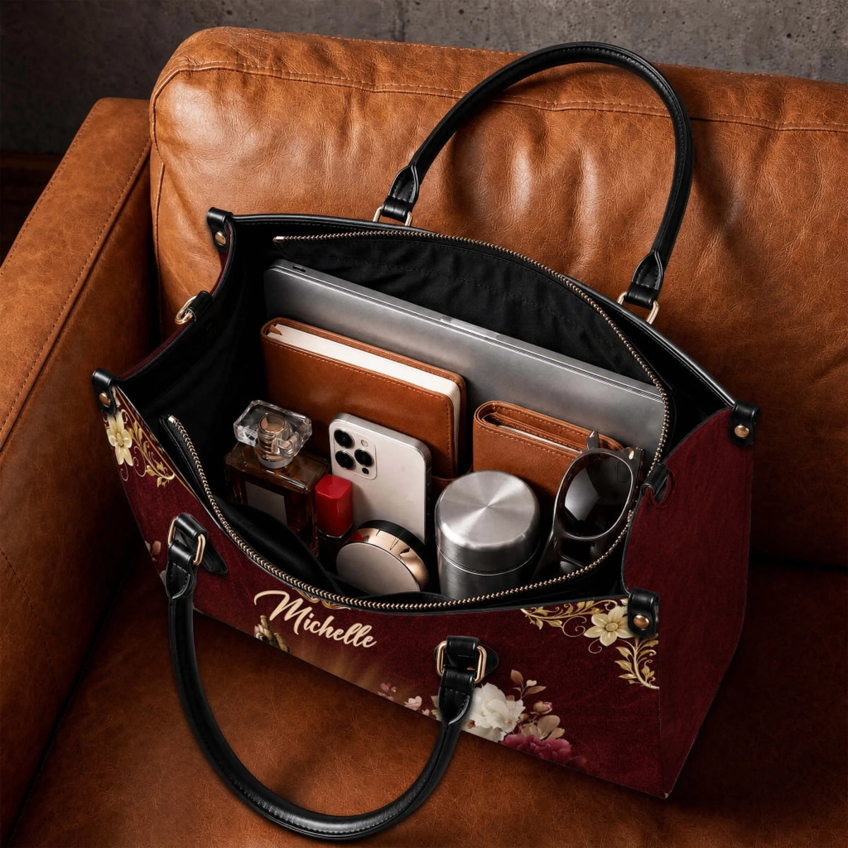 Spacious personalized Michelle religious handbag filled with daily items like a laptop, notebook, and accessories.