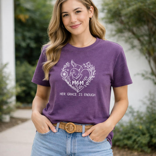 Woman wearing a purple t-shirt with a graphic design and text, standing outdoors.