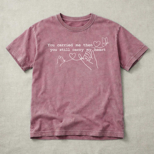 Mauve t-shirt with text and heart graphics on a beige fabric background