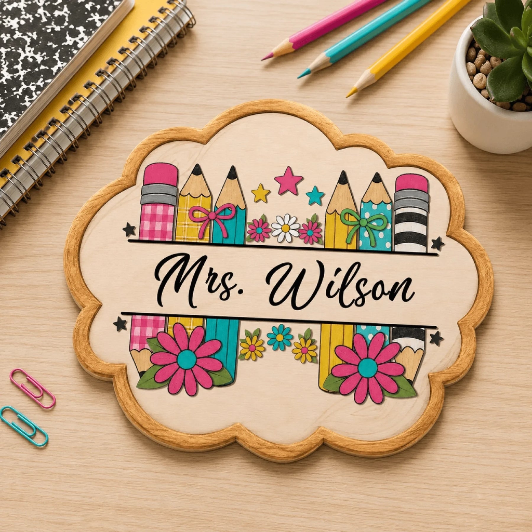 Personalized classroom wooden sign featuring pencils and flowers, resting on a desk with notebooks and pencils.
