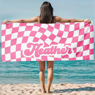 Custom name beach towel featuring a trendy pink and white wavy checkerboard pattern, perfect for summer pool days.