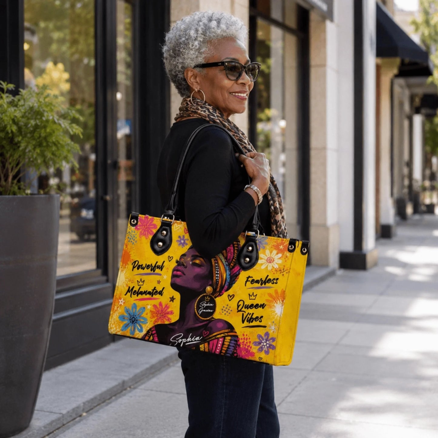 Stylish woman with gray hair wearing sunglasses and carrying a personalized melanated queen vibes tote bag accessory