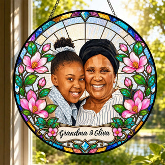 A custom stained glass suncatcher featuring a photo of a grandma and granddaughter with floral borders and personalized name text.