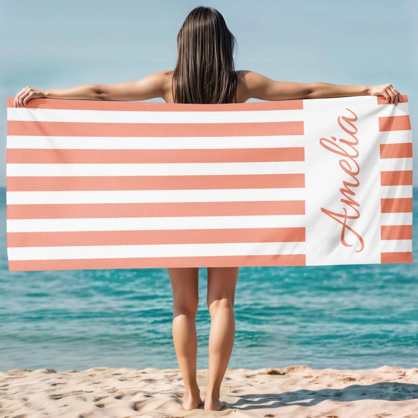 Custom peach striped beach towel with the name Amelia displayed, perfect for a sunny day at the ocean or pool.