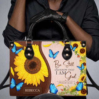 Close up of a personalized sunflower and butterfly handbag featuring the inspirational Be Still and Know quote.