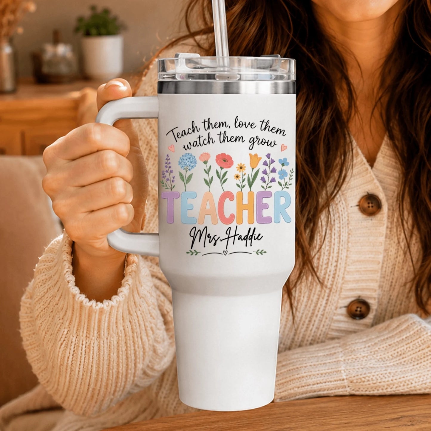 Close-up of a person holding a white teacher tumbler with wildflowers and the personalized name Mrs. Haddie.
