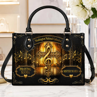 Customizable black handbag with a musical treble clef cross, cathedral background, and personalized name text.