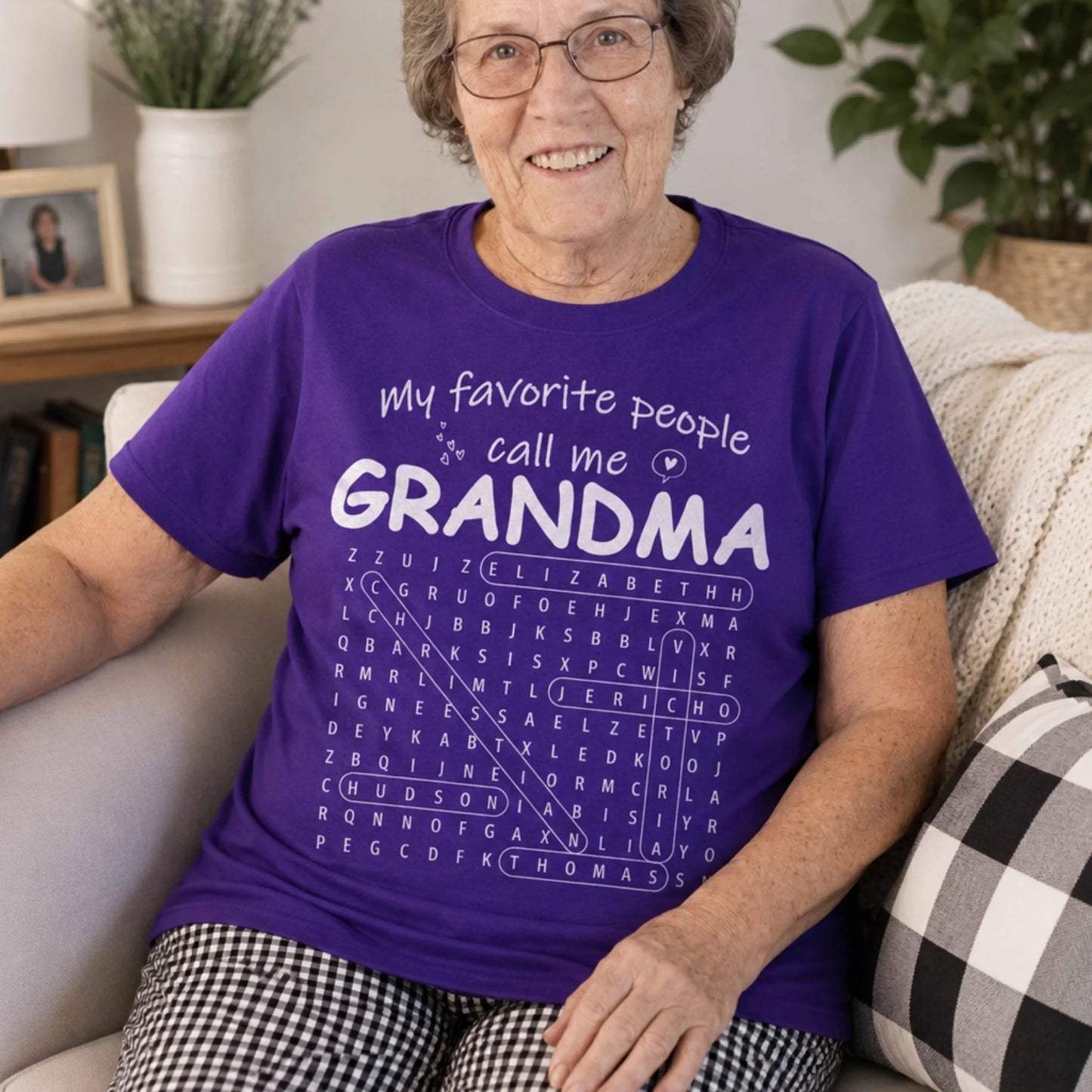 A woman wears a purple t-shirt featuring a personalized word search puzzle design with the custom text Grandma gift.