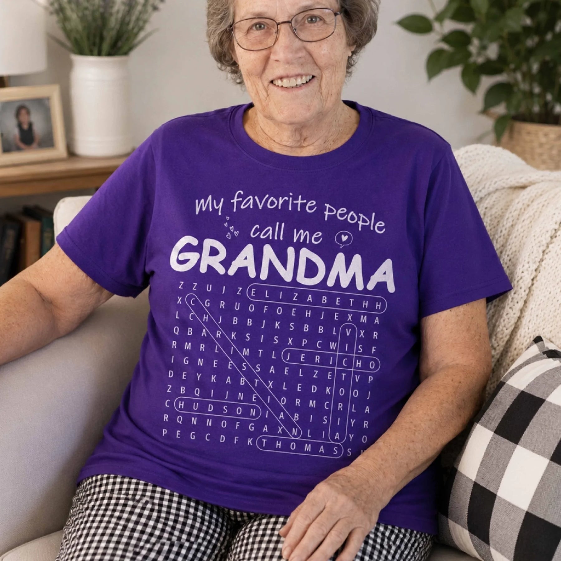 A woman wears a purple t-shirt featuring a personalized word search puzzle design with the custom text Grandma gift.