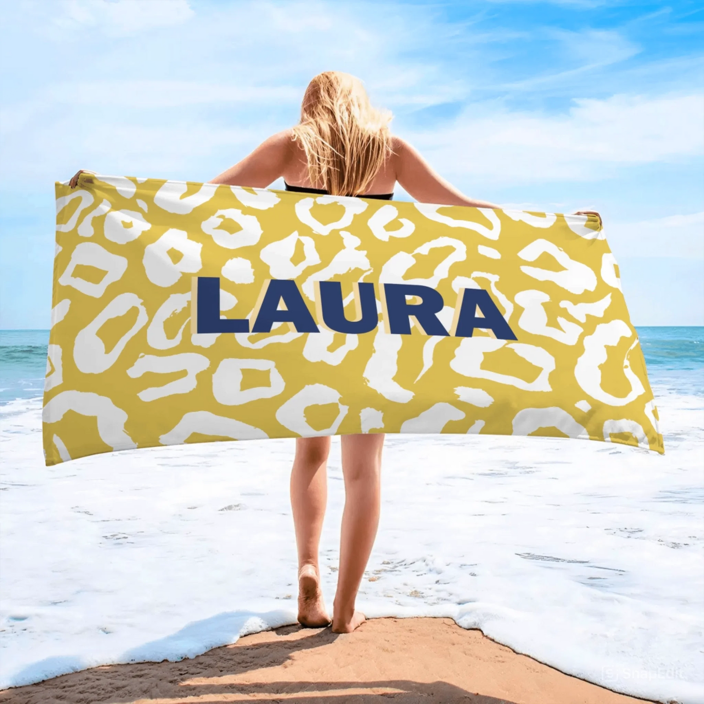Woman showcasing a yellow and white leopard print beach towel with the custom name Laura, perfect for a personalized summer gift.